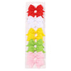 A collection of colorful handmade ribbon bow hair clips for kids in red, white, yellow, and green.