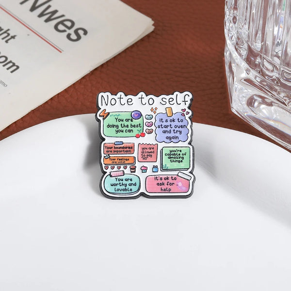 An enamel lapel pin with a note to self design featuring encouraging messages like being the best and worthy