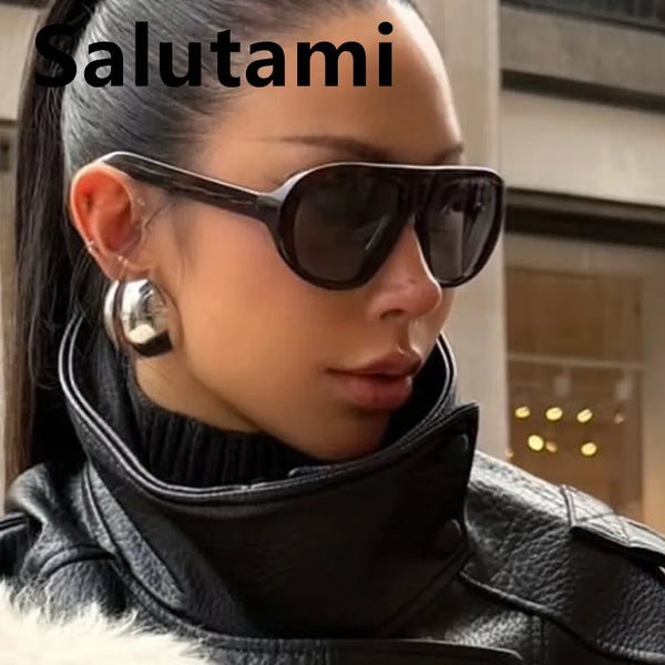 A close-up of a woman wearing dark brown vintage gradient leopard print sunglasses and a black leather jacket.