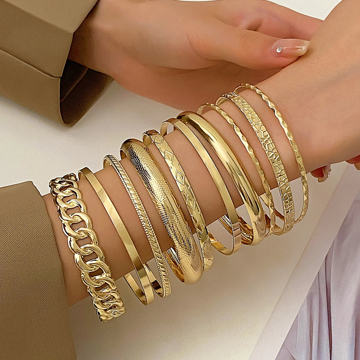 A stack of gold geometric minimalist bracelets worn on a wrist.