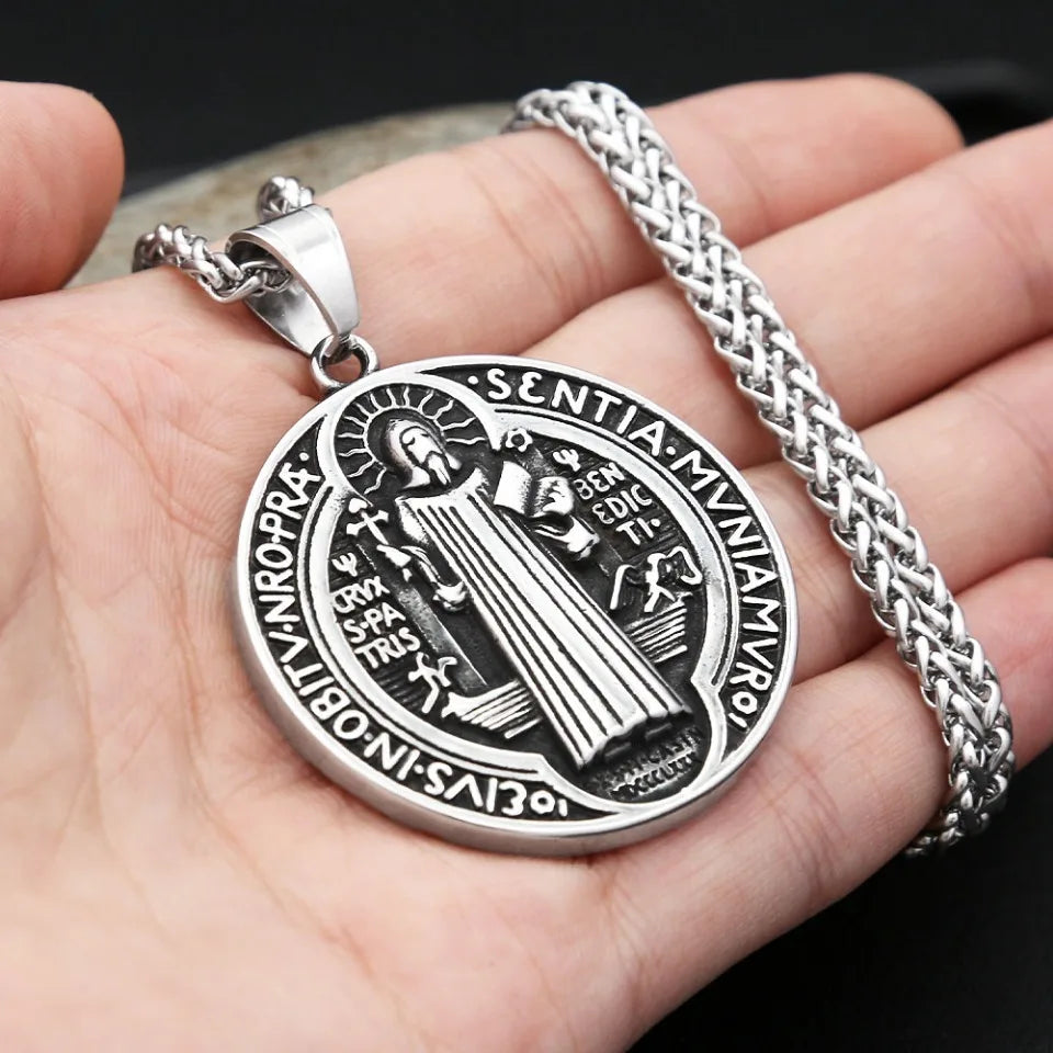 A vintage stainless steel pendant necklace featuring a Saint Benedict exorcism design on a silver chain.