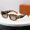 Pair of brown leopard print sunglasses resting on a white surface next to an orange box.