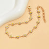 Gold enamel daisy chain anklet with small yellow flowers on a beige background