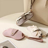 A light pink PU leather eyewear storage case with a gold chain and white wooden sticks is displayed on a beige surface.