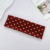 A maroon fabric headband with small white polka dots is displayed on a white surface.