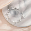 A sterling silver double heart charm bracelet is displayed on a white surface.