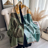 A draped olive green and khaki plaid cashmere scarf wrapped around a mannequin.