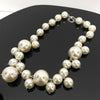 A strand of round, off-white simulated pearls forming a choker necklace displayed on a dark surface.