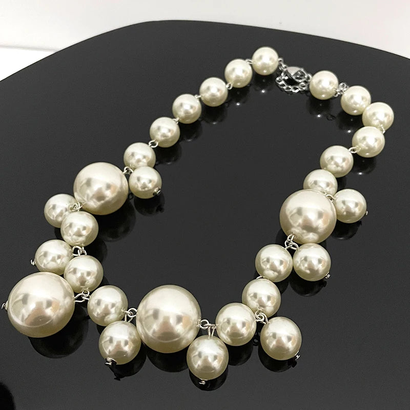 A strand of round, off-white simulated pearls forming a choker necklace displayed on a dark surface.