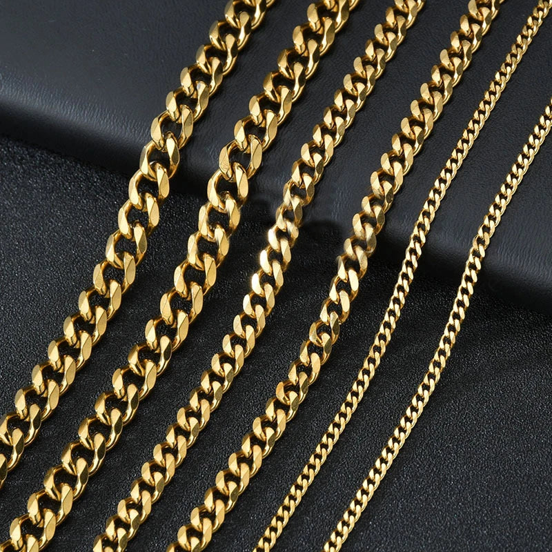 A close-up of several gold Cuban link chain necklaces laid out on a dark surface.