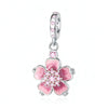 Pendientes colgantes plateados con un dije floral rosa y pequeñas piedras rosas y un aro de plata.