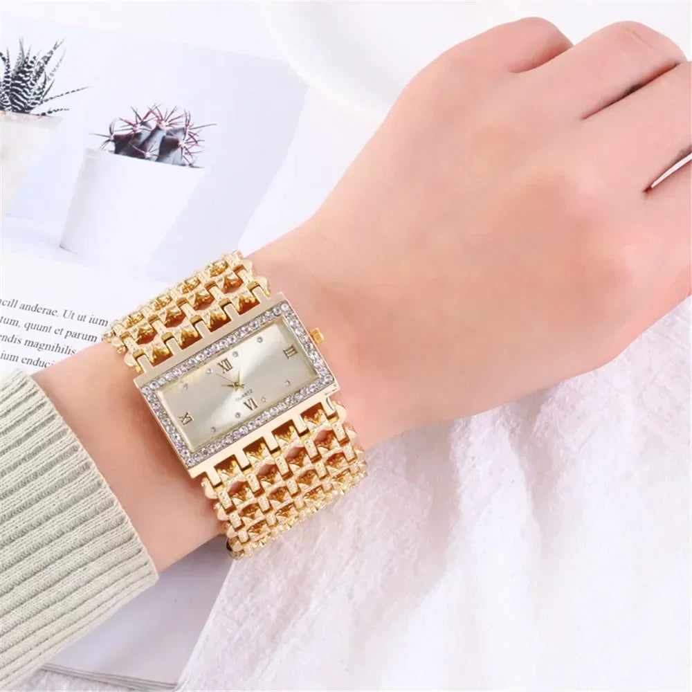 A close-up of a fashion quartz diamond watch with a gold stainless steel bracelet worn on a hand.