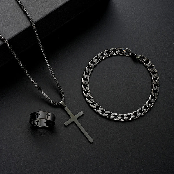 A set of men's stainless steel jewelry including a chain necklace, a cross pendant, and a ring displayed on a dark surface.