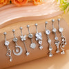 A set of gold dangle curved belly piercing jewelry featuring heart, flower, and crescent moon charms.