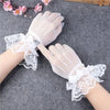 Pair of sheer lace fishnet evening gloves worn on a hand against a gray background.