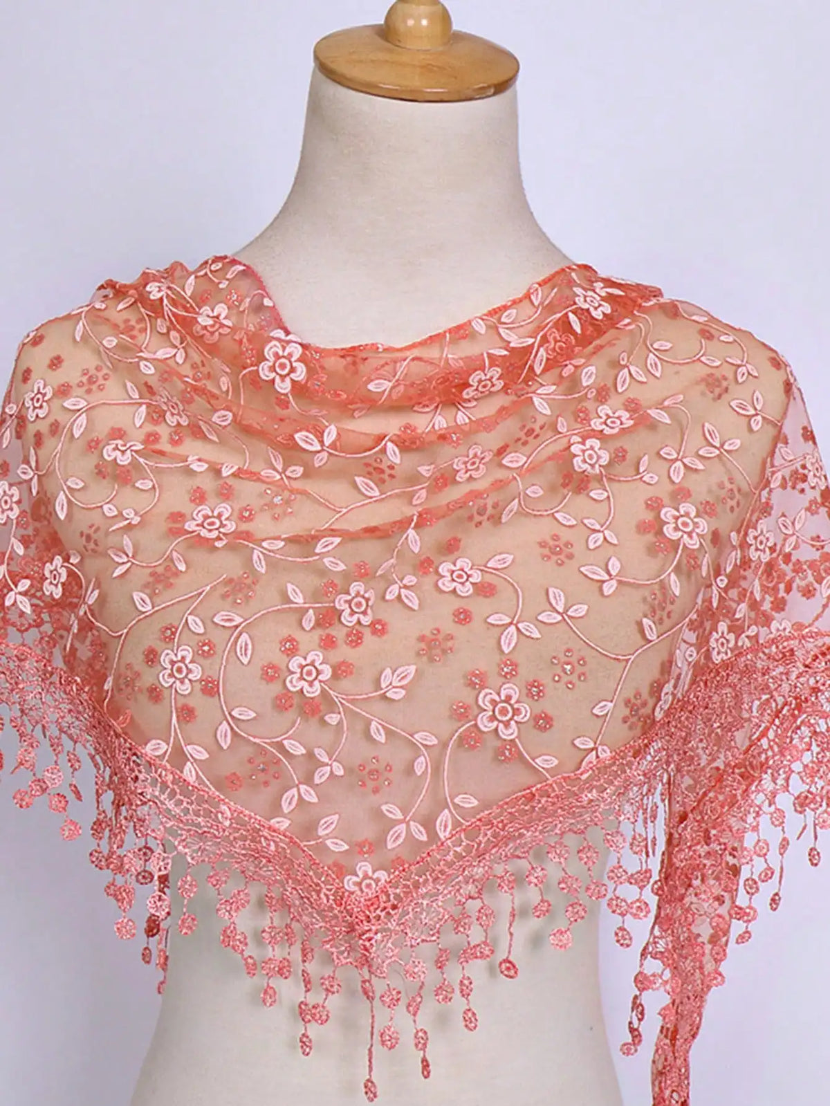 A sheer peach floral lace scarf draped around a mannequin's neck and shoulders.