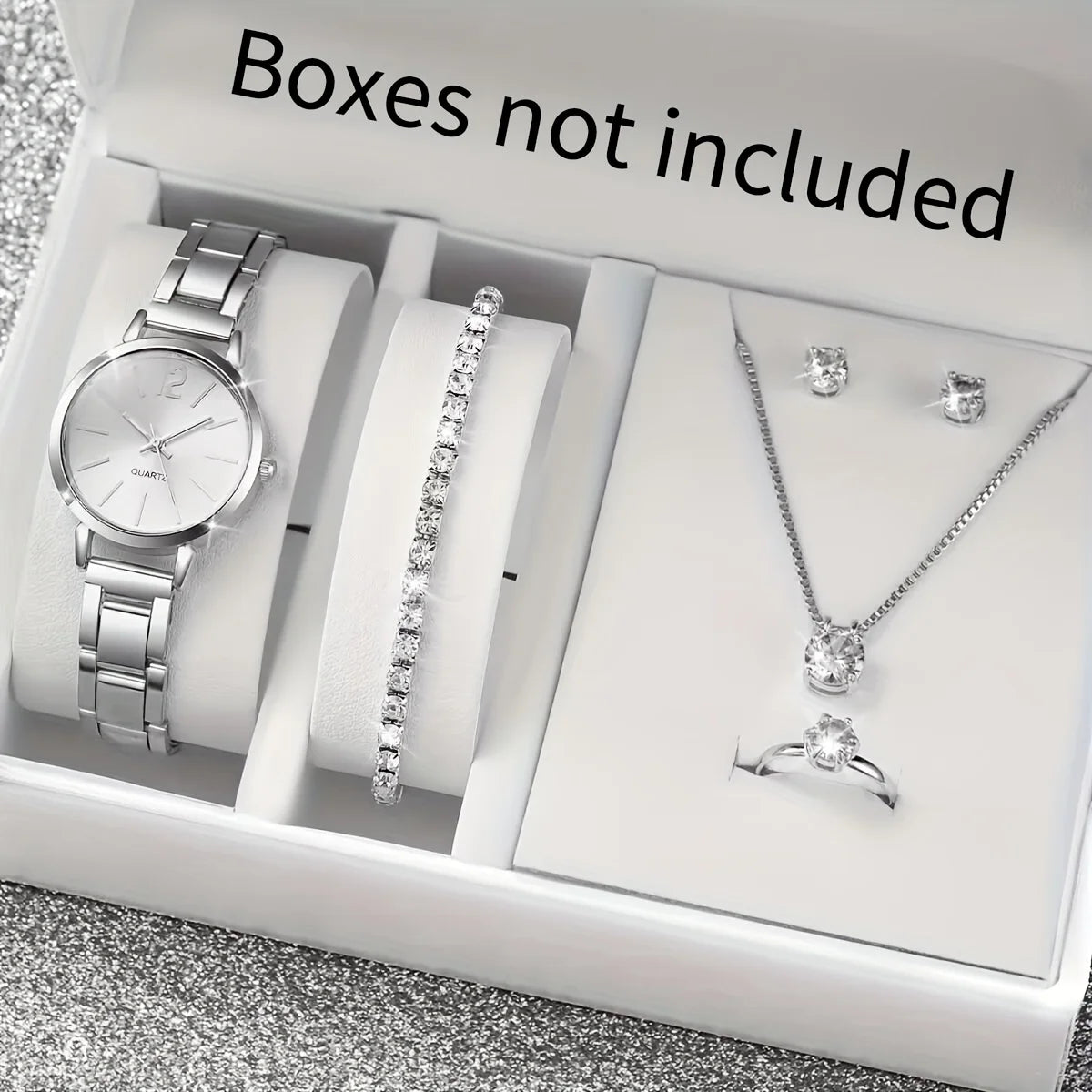 A white box interior shows a watch, a diamond necklace, and a ring, with text stating boxes are not included.