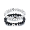 A stack of white and gray marbled beads forming a string bracelet with a yin yang charm.