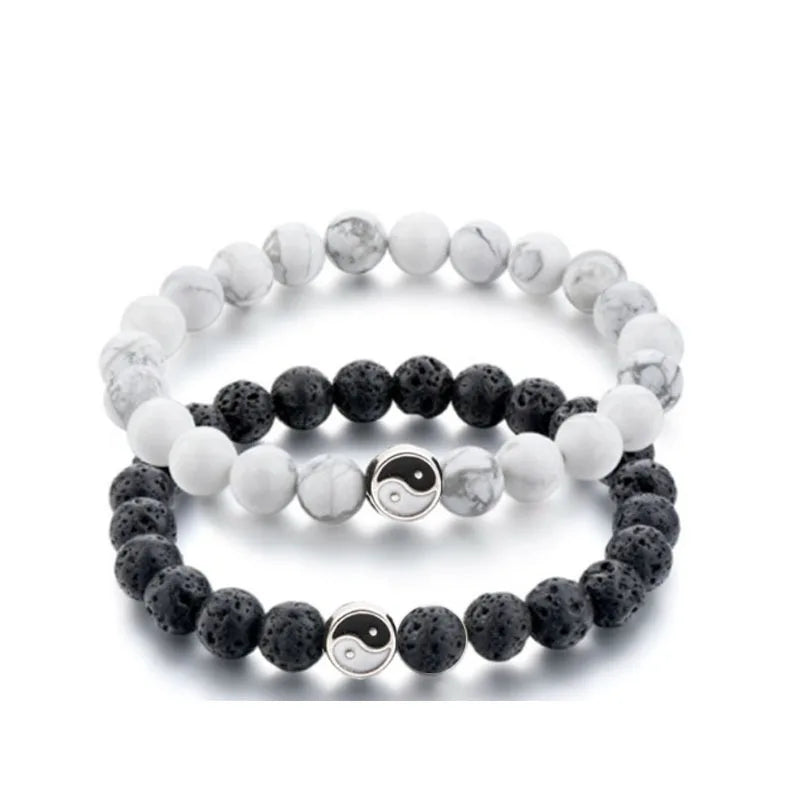 A stack of white and gray marbled beads forming a string bracelet with a yin yang charm.