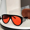 Oversized fashion pilot sunglasses with black frames and bright orange lenses displayed on a white surface.