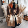 A luxury plaid cashmere feel scarf and shawl wrap draped over a dark garment.