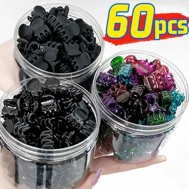 A hand holds several clear containers filled with a set of black and colorful adjustable hair claw clips.