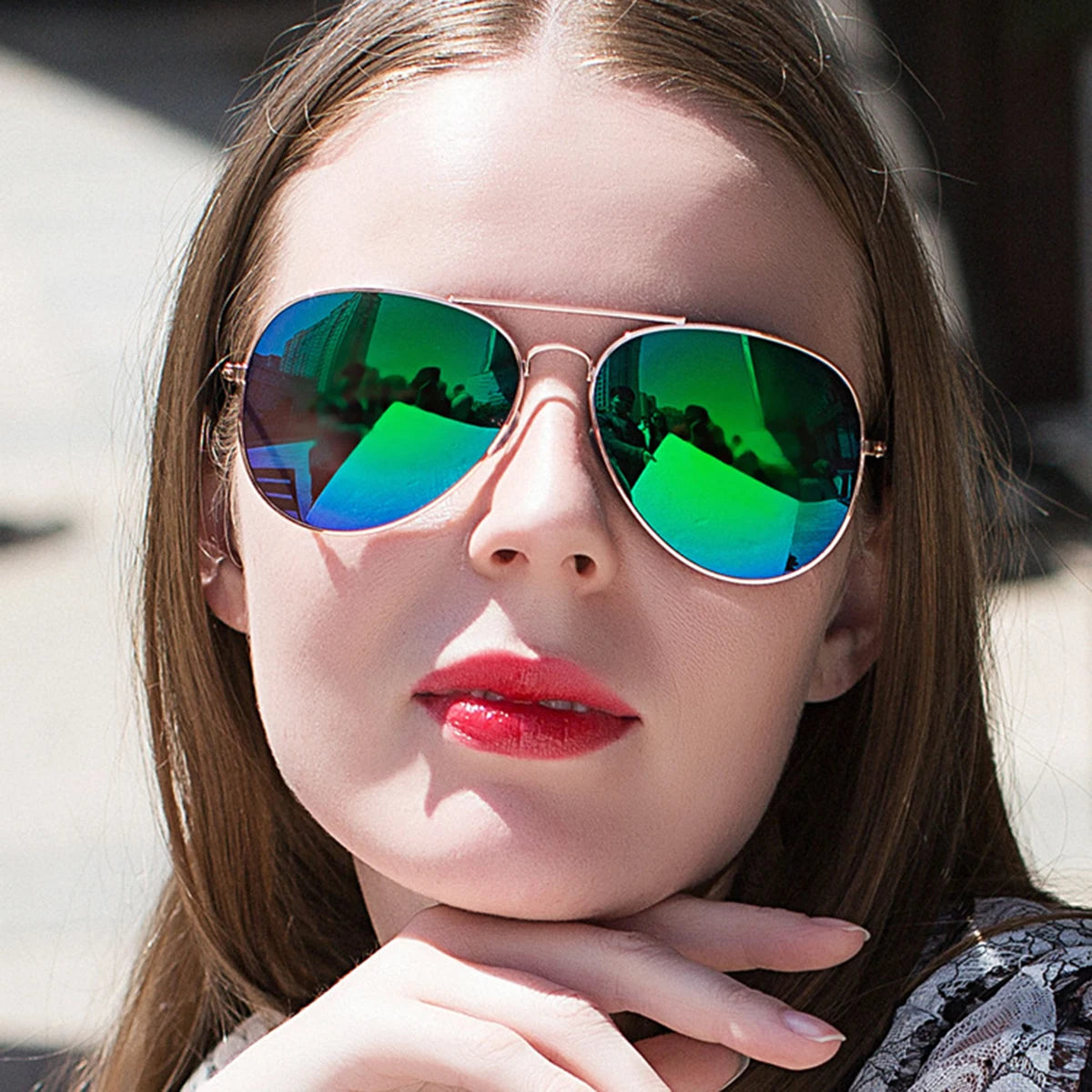 A young woman wearing aviator sunglasses with iridescent green and blue lenses and gold frames.