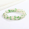 Una pulsera hecha de pequeñas cuentas blancas y verdes, que parece una cadena corporal.