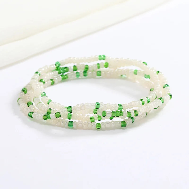 Una pulsera hecha de pequeñas cuentas blancas y verdes, que parece una cadena corporal.