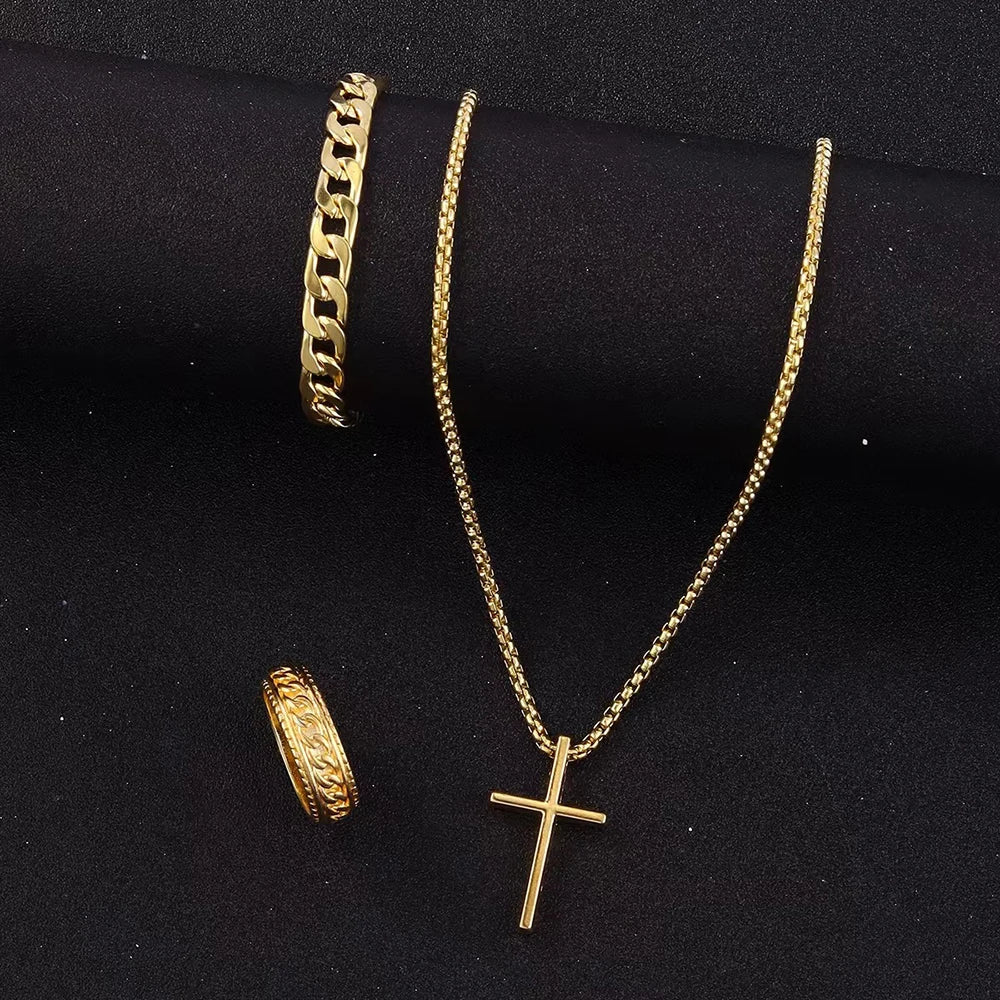 Collier croix en acier inoxydable doré et bracelet chaîne doré sur fond sombre.