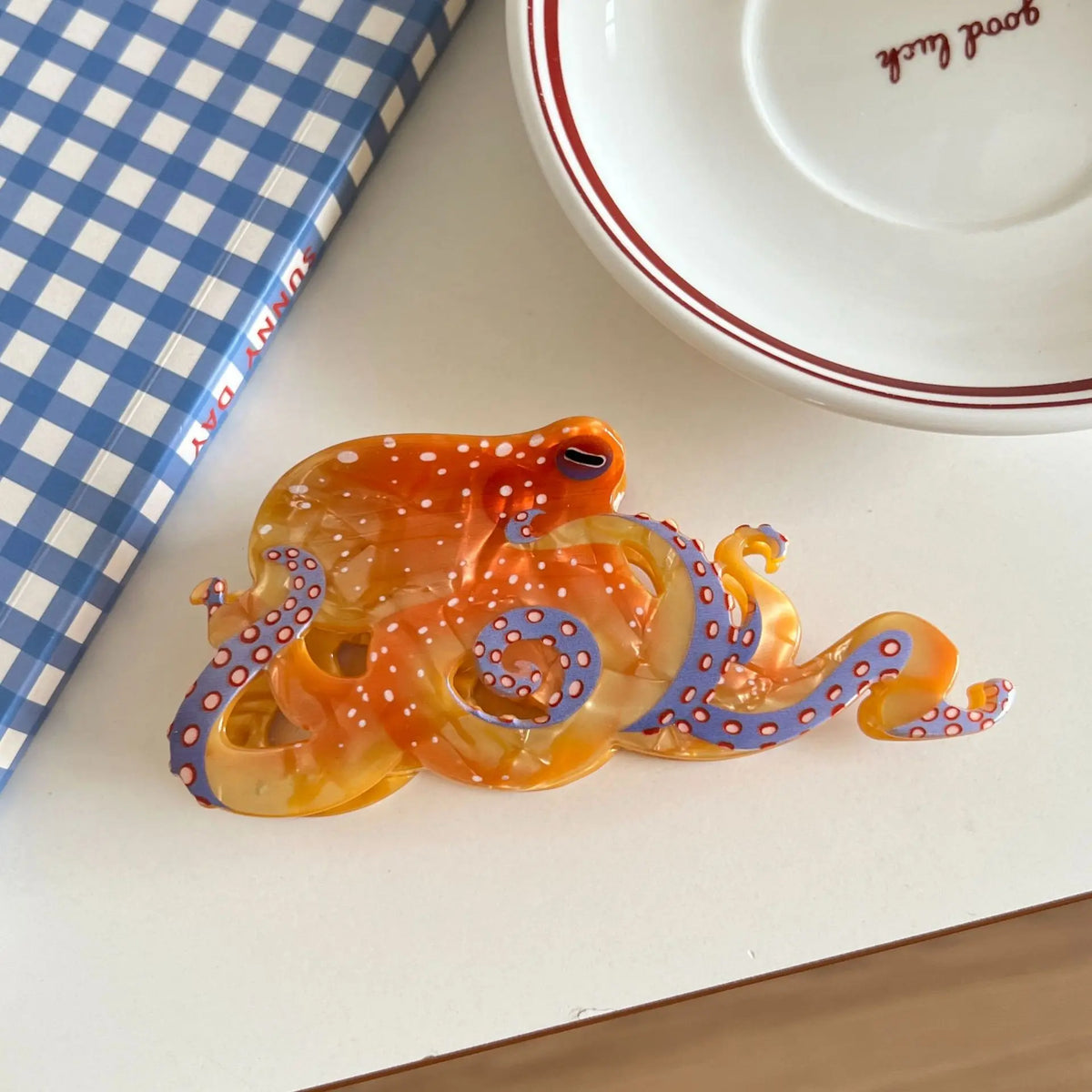 Un amas de pinces à cheveux en forme d'œillet d'octopus colorées et translucides avec des motifs orange et bleu, posées sur u