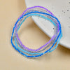 A collection of luminous glow-in-the-dark beaded anklets in shades of blue and purple displayed on a white surface.