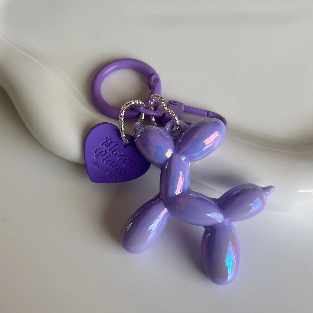 A purple jelly cartoon dog keychain with a purple heart tag and silver chain.