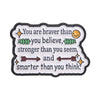 A black enamel pin featuring the quote You are braver than you believe stronger than you seem and smarter than you think.