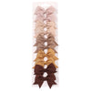 A set of handmade ribbon bow hair clips for kids in various neutral tones including beige, tan, and brown.