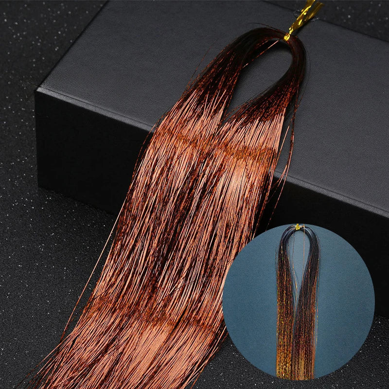 A bundle of reddish-brown hair extensions with glitter strands is displayed against a dark background.