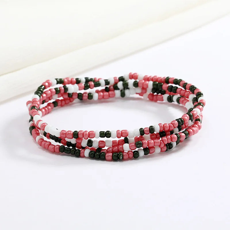 Una pulsera hecha de pequeñas cuentas rojas, blancas y negras mostrada sobre un fondo blanco.