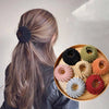 A collection of elegant black, green, and orange horsetail hair clips arranged on a wooden plate.