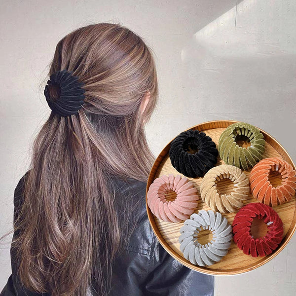 A collection of elegant black, green, and orange horsetail hair clips arranged on a wooden plate.