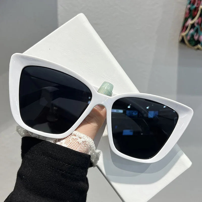 White retro cat eye sunglasses with light green accents resting on a white surface.