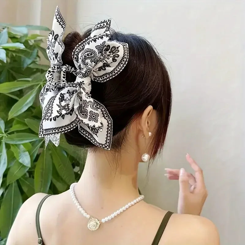 Una mujer con peinado negro adornado con un elegante clip para el cabello de patrón de anacardo vintage y un collar de perlas
