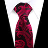 A close-up of an elegant men's floral paisley silk necktie in black and deep red on a white shirt.