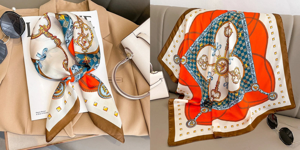 A floral print silk scarf featuring blue, orange, and white patterns displayed next to a light-colored leather bag.