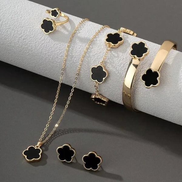 A set of five gold-toned bracelets featuring black enamel plum blossom charms displayed on a white surface.