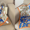 A blue and white floral print silk scarf draped on a wooden tray in a light beige interior setting.