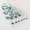 A collection of clear glass ear stretching plugs and tunnels arranged in a white container.