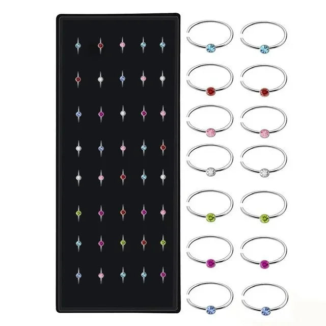 A set of stainless steel nose studs and rings for body piercing, featuring various designs.