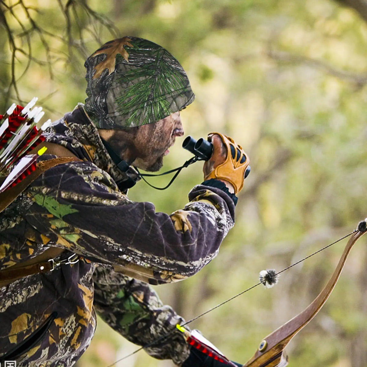 A person wearing a camouflage thermal beanie is aiming a bow and arrow outdoors.