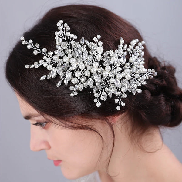 A close-up of a dark-haired woman wearing a bridal headpiece made of sparkling pearl and rhinestone flowers.