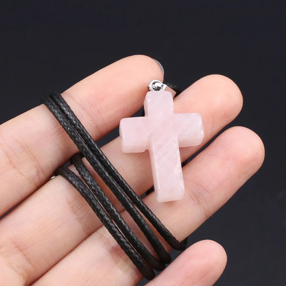Pinkes Tigerauge-Agat-Kreuz-Anhänger-Halskette an der Hand mit schwarzem Band